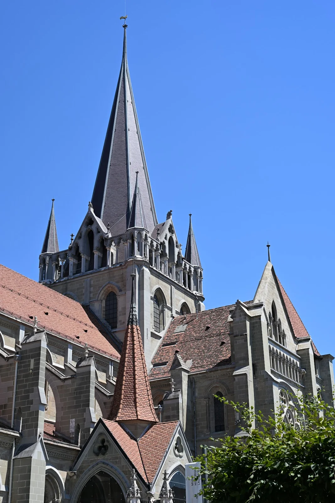 Torres, telhados e fachada da Catedral de Lausanne sob céu azul