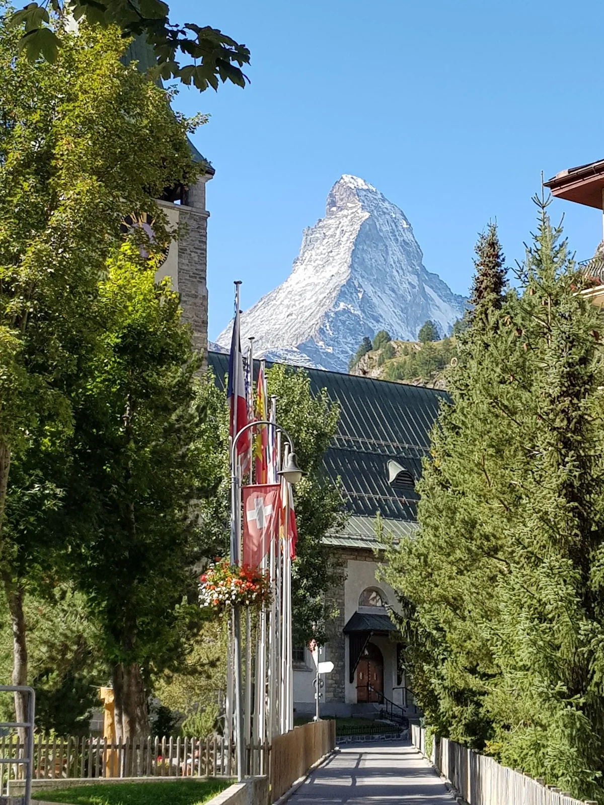 Matterhorn visto entre árvores, edifícios e bandeiras em Zermatt