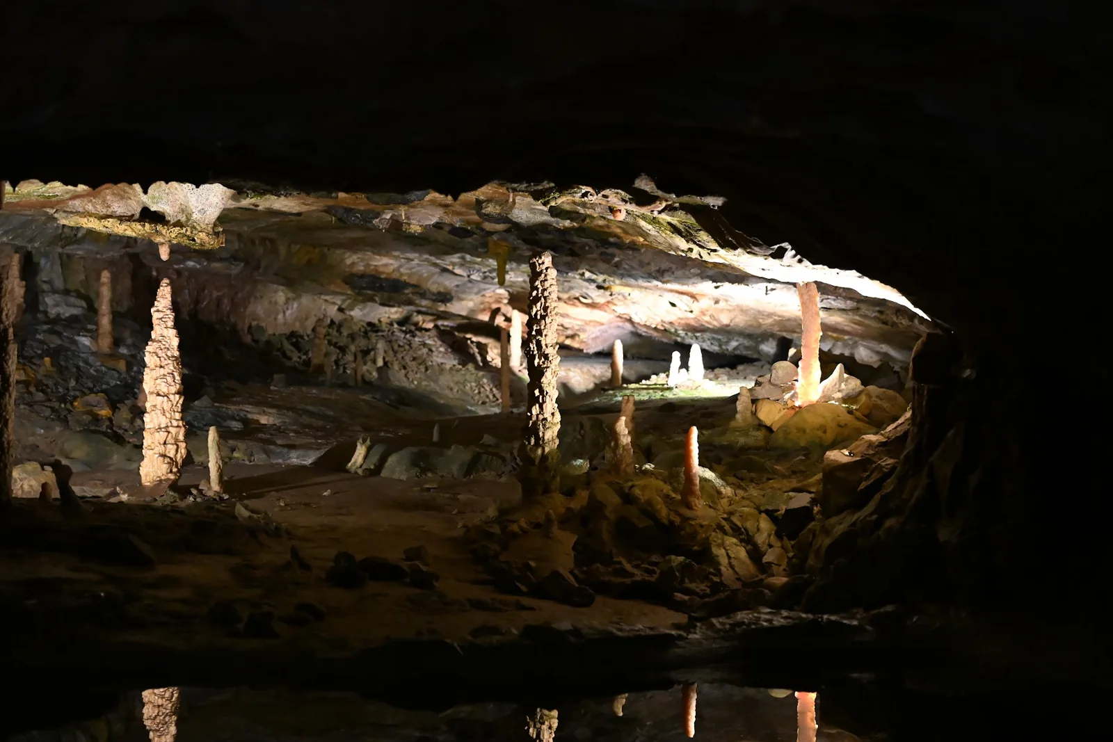 Formações rochosas iluminadas e refletidas na água dentro das Grutas de São Beatus