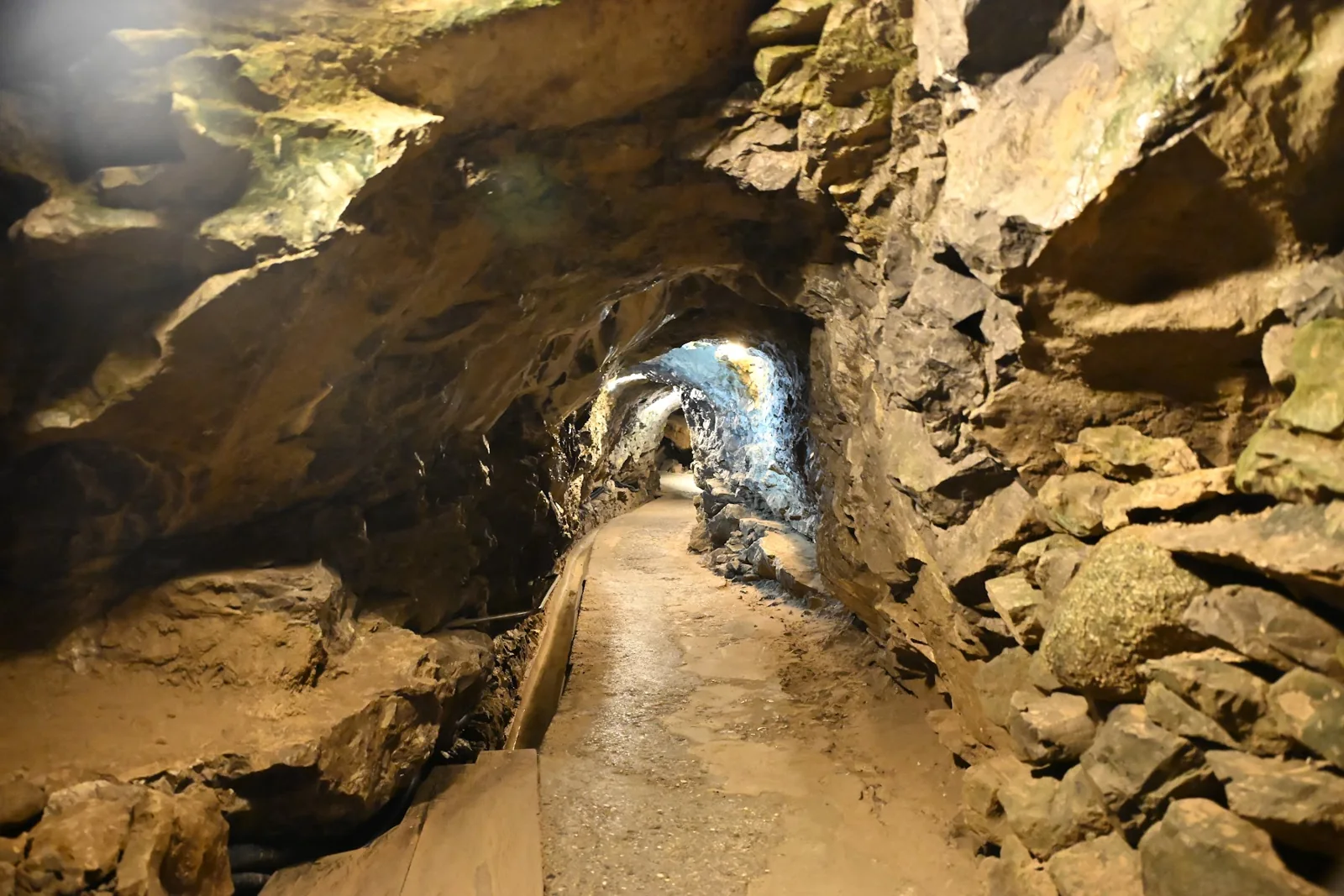 Caminho iluminado entre paredes de rocha nas Grutas de São Beatus