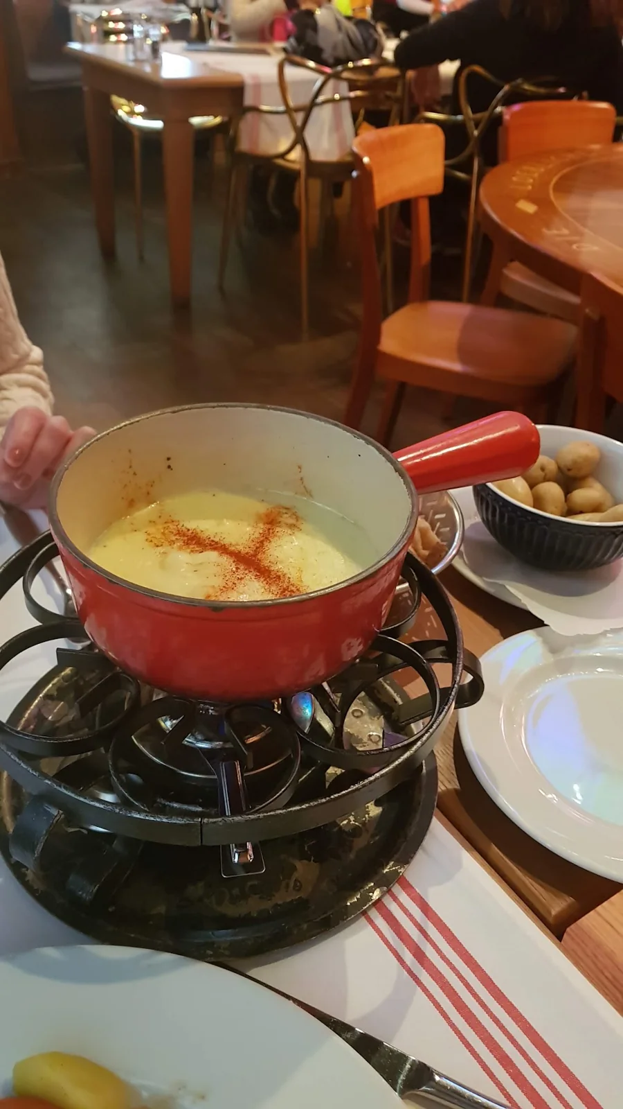 Fondue de queijo em uma panela vermelha sobre um réchaud