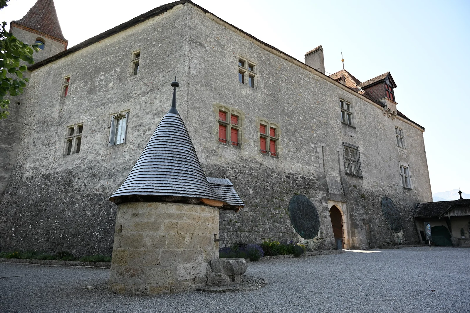Fachada externa do Castelo de Gruyères e poço no espaço diante dela