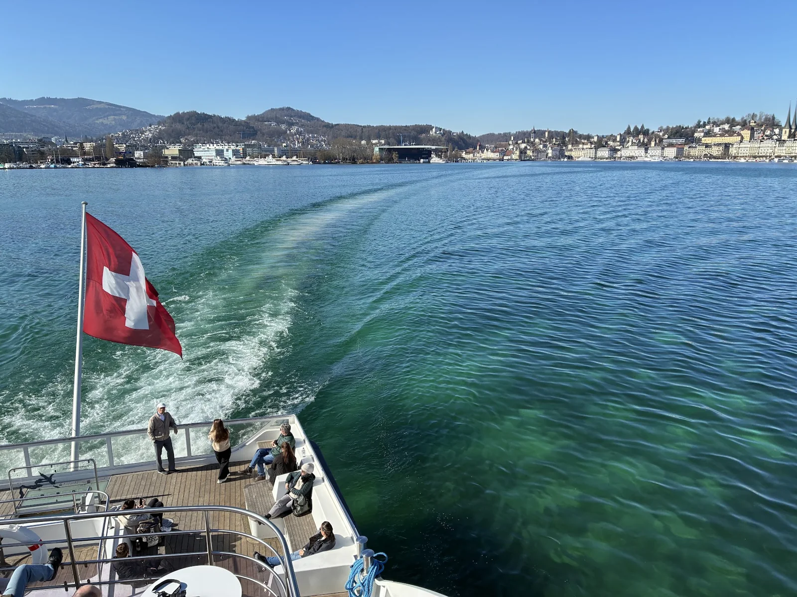 Bandeira suíça na popa de um barco com a cidade de Lucerna ao fundo