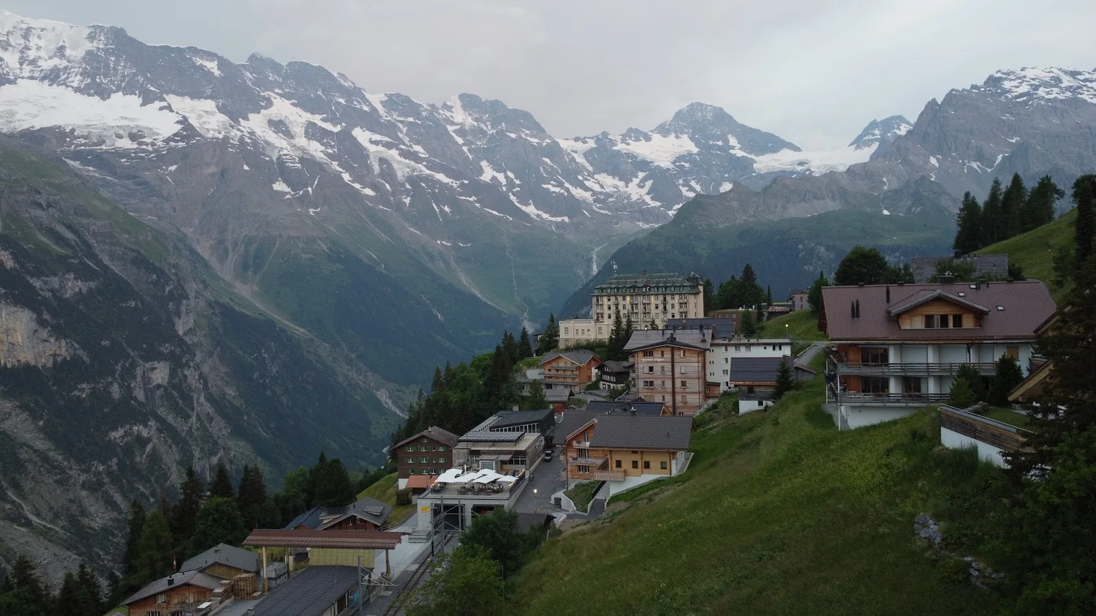 Casas de Mürren na encosta, com paredões e montanhas nevadas ao fundo