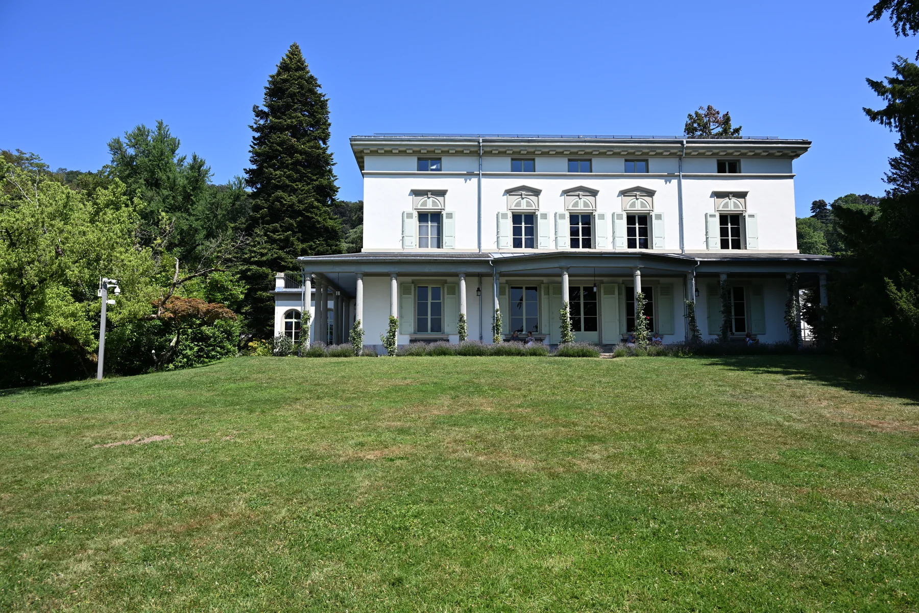 Fachada do Manoir de Ban vista do gramado, com árvores ao redor