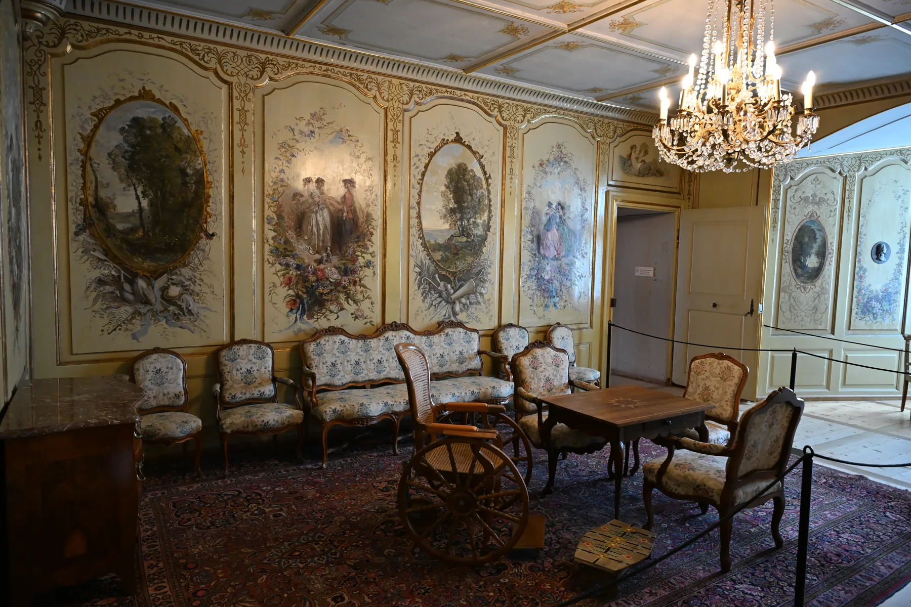 Salão do castelo com painéis pintados, cadeiras, mesa e lustre