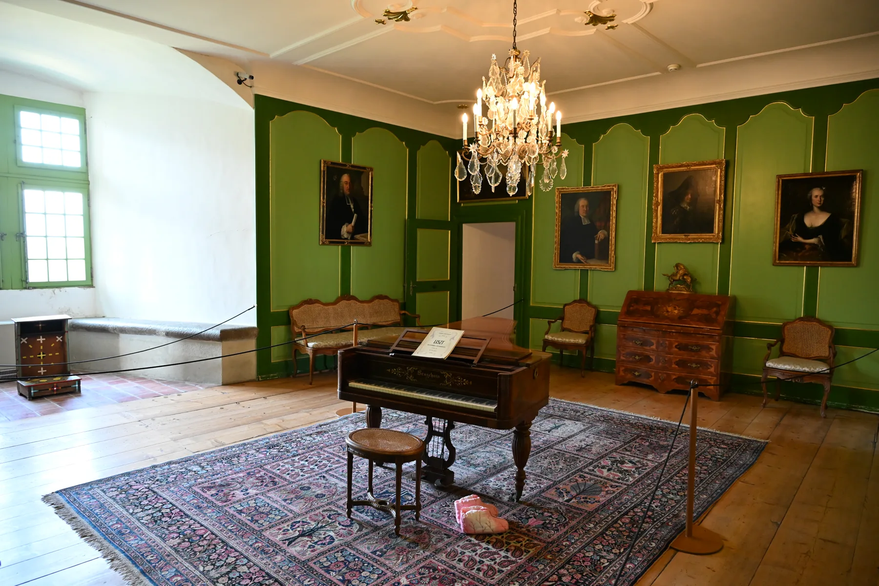 Sala do castelo com paredes verdes, retratos e móveis de madeira