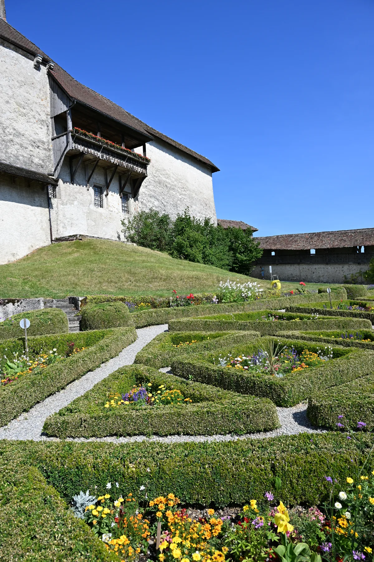 Canteiros geométricos e caminho no jardim junto à fachada do castelo