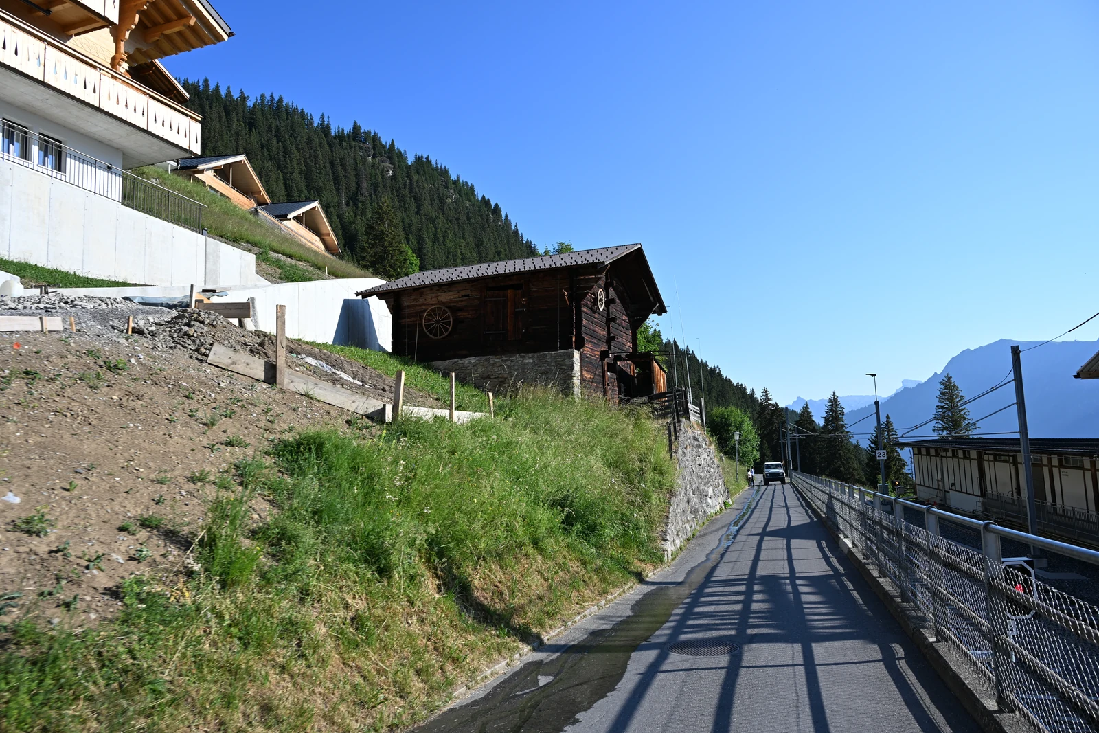 Rua inclinada junto a construções e trilhos em Mürren