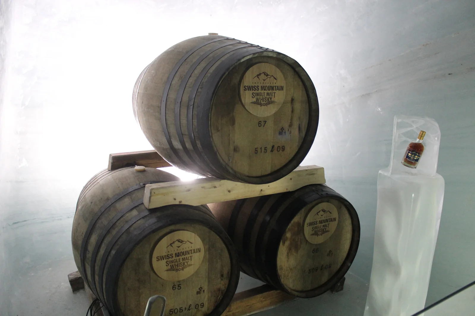 Três barris de Swiss Mountain Single Malt Whisky e uma garrafa em nicho de gelo