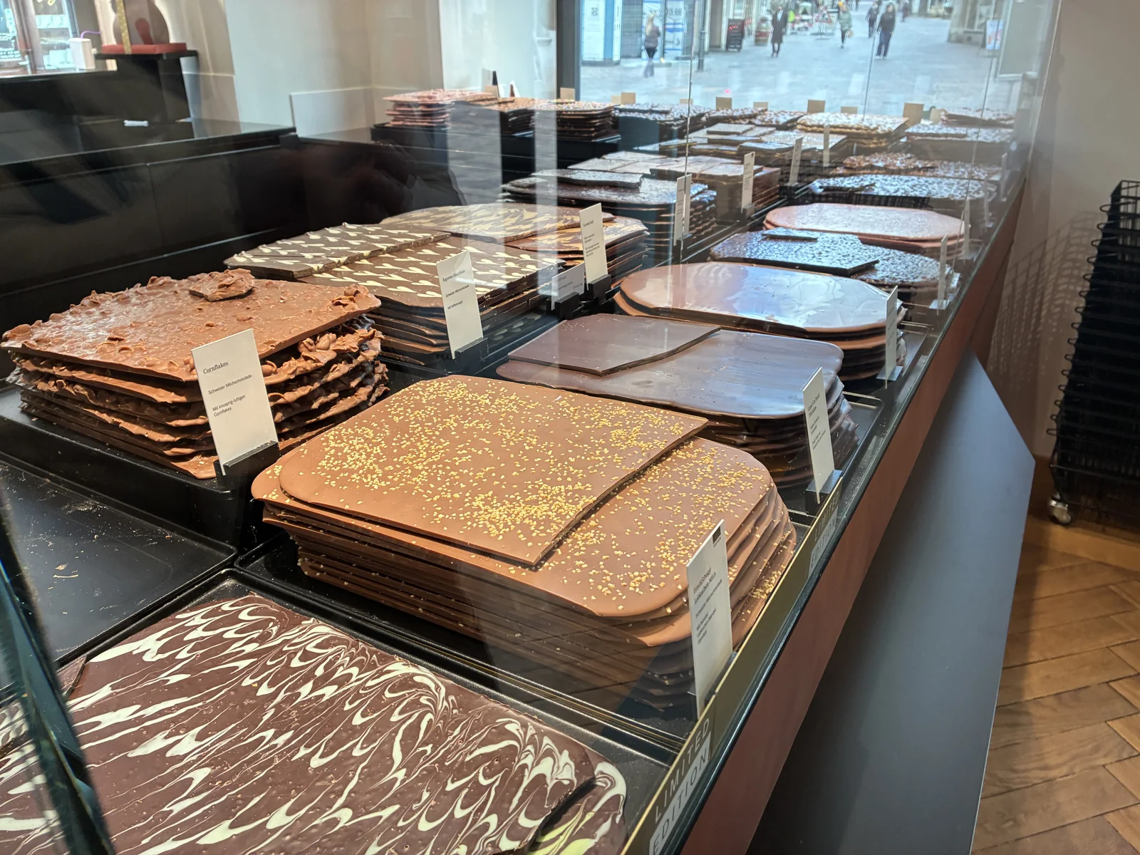 Grandes placas de chocolate com coberturas diferentes, expostas em uma vitrine