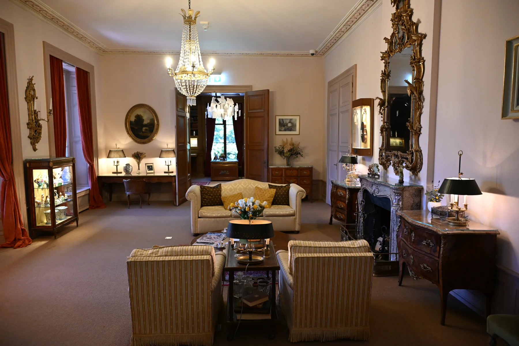 Sala expositiva do Manoir de Ban com sofás, lareira e lustre