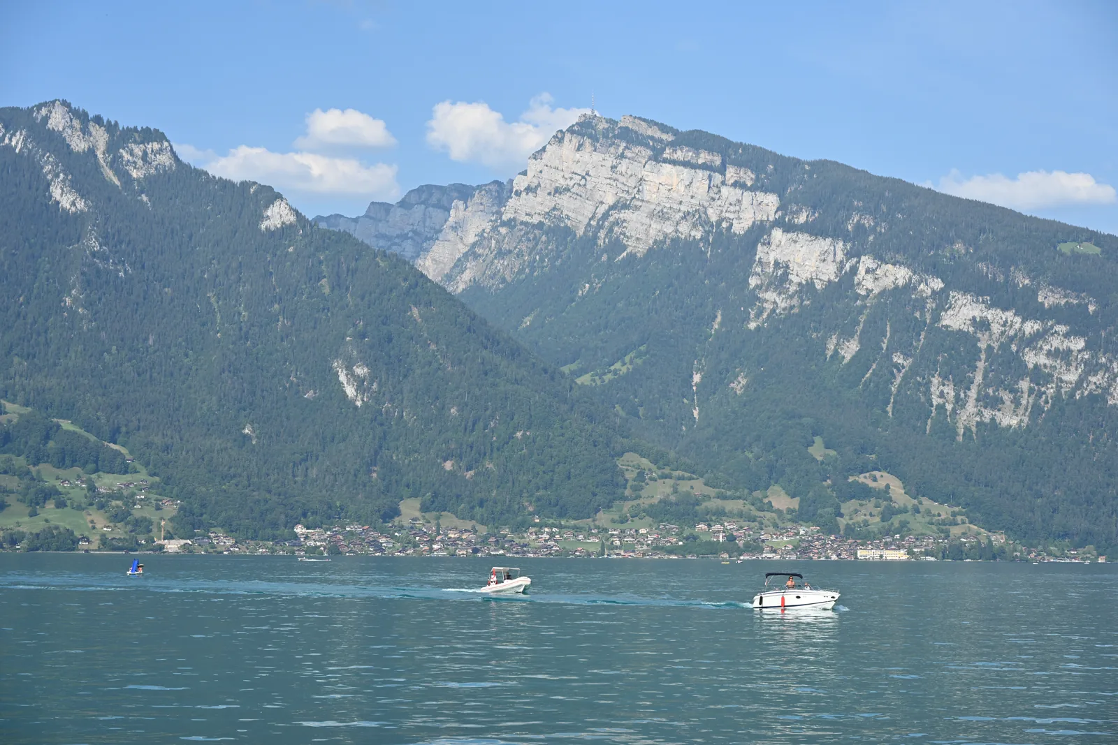 Pequenos barcos no Lago Thun e montanhas na margem oposta, vistos de Spiez