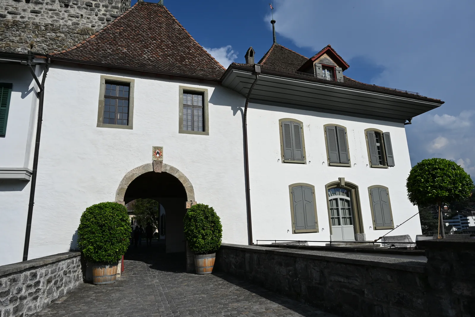 Passagem em arco junto ao castelo, com piso de pedra e vasos de plantas