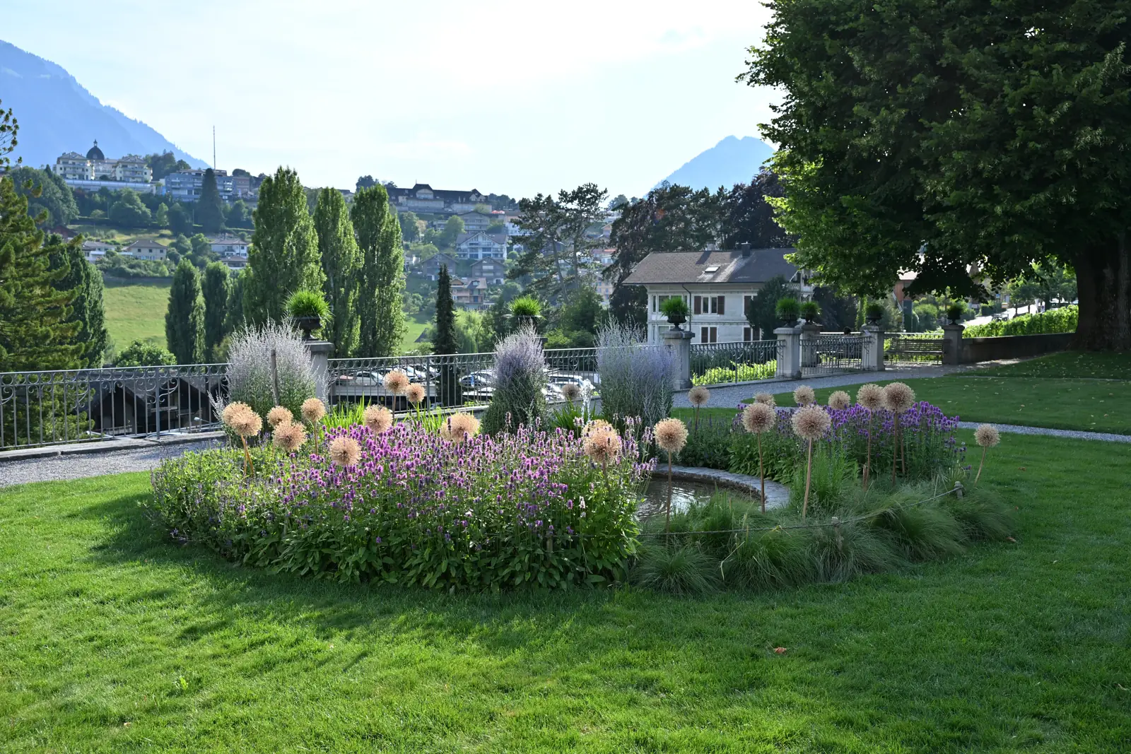 Canteiros floridos e fonte diante da balaustrada do jardim de Spiez